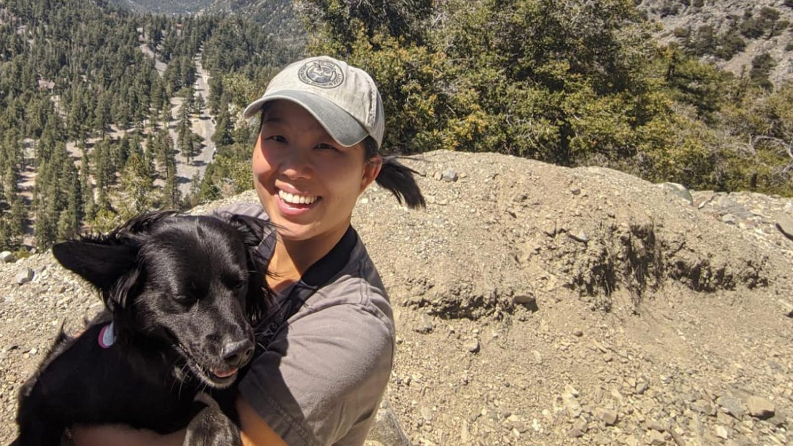 Professor Charlotte Chang holding black dog in outdoor environment