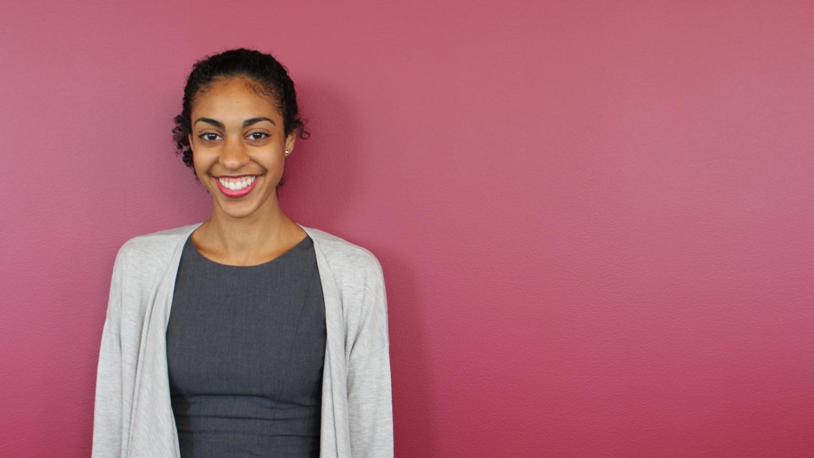 Leah Donnella stands against a magenta wall.