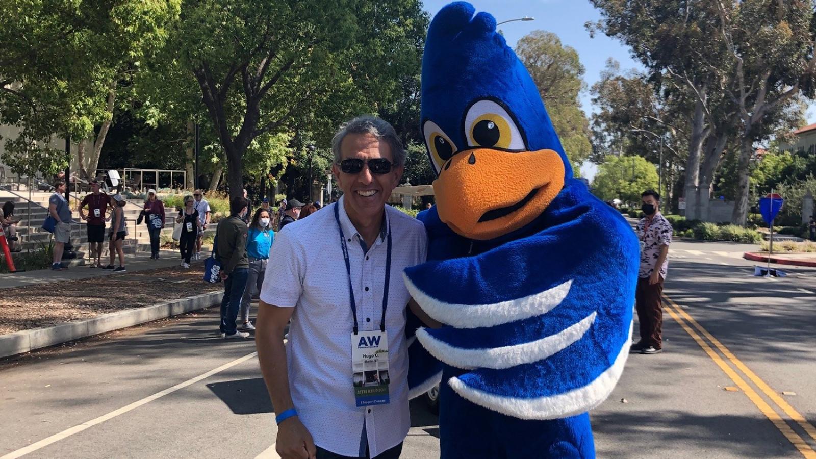 Hugo Martín stands next to Cecil the Pomona College mascot on a street.