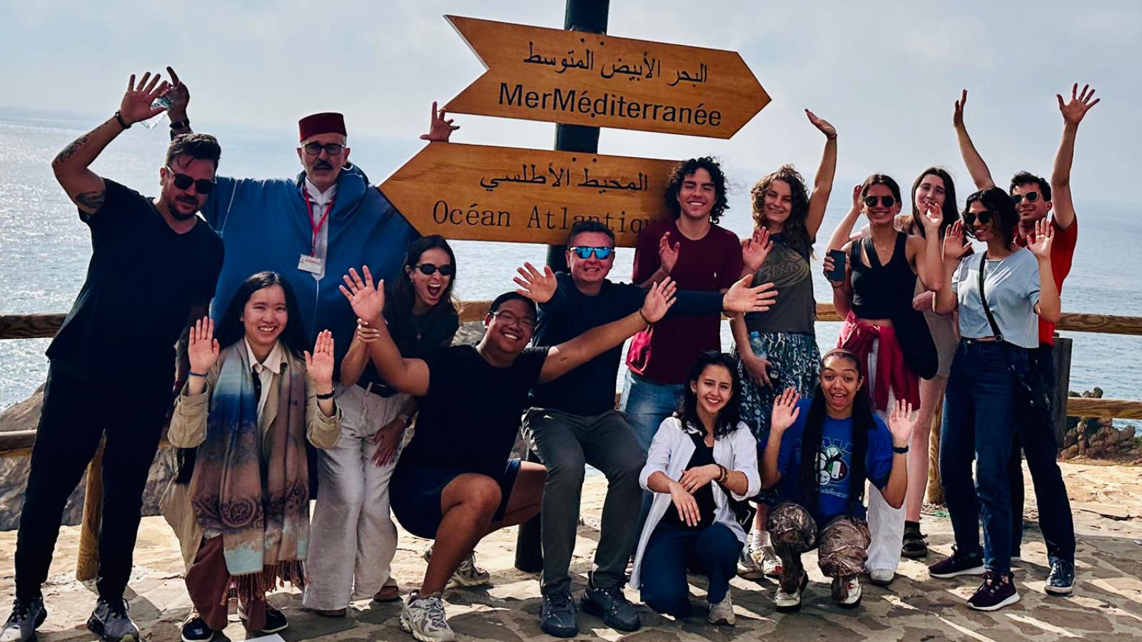students and others in front of the ocean in Assilah