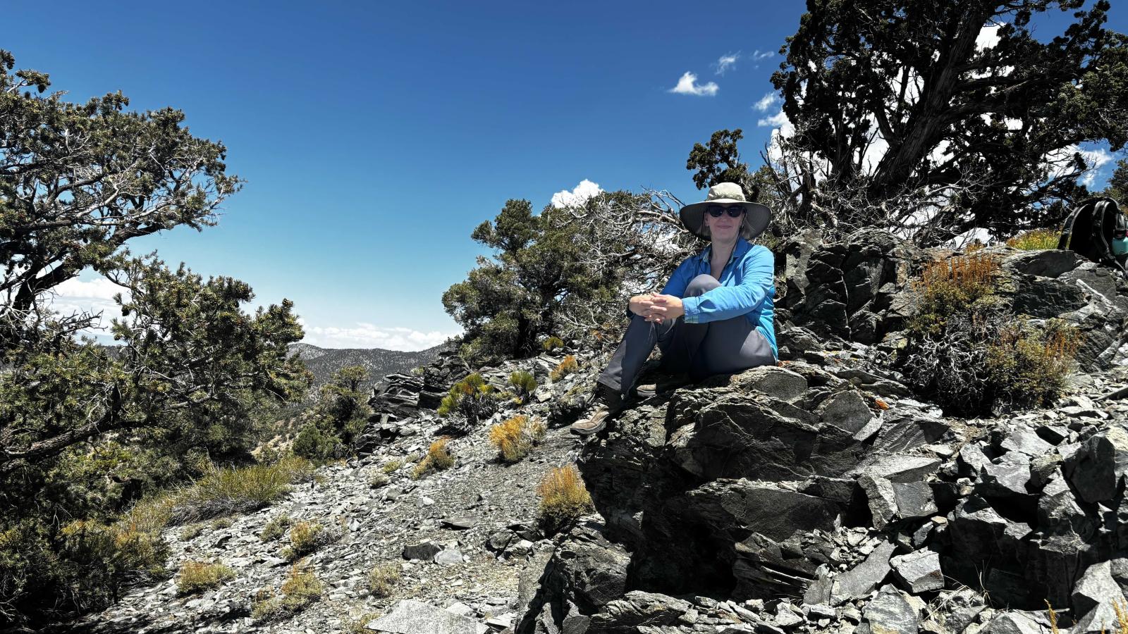 Nikki Moore sits on a pile of large rocks in the Sierra Nevada