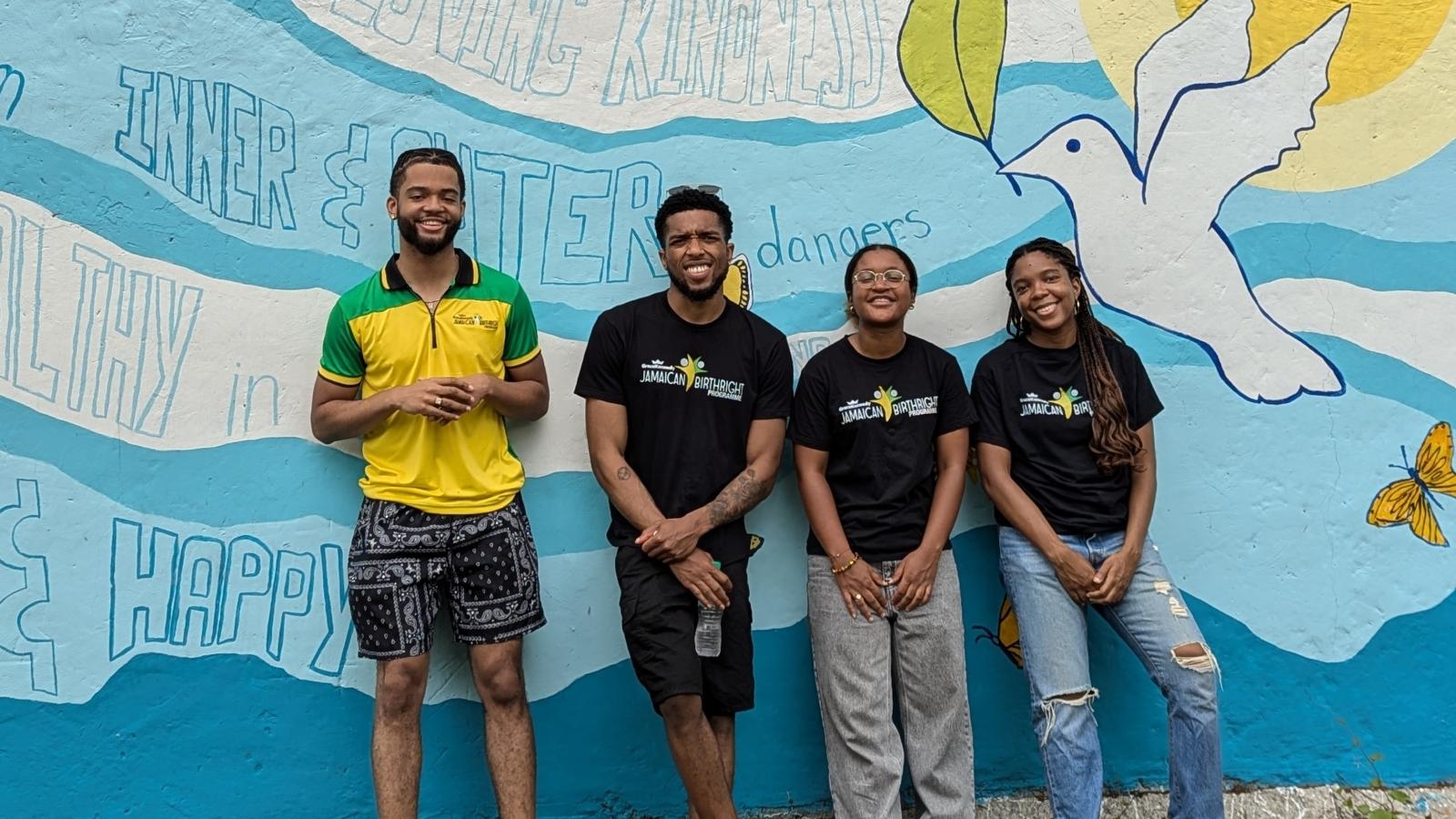 Four students stand in front of painted wall