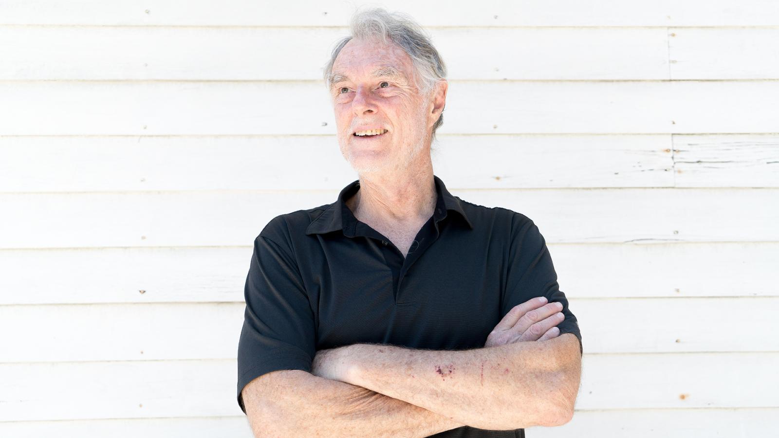 Professor Gary Smith standing in front of a white wall with arms folded across chest.
