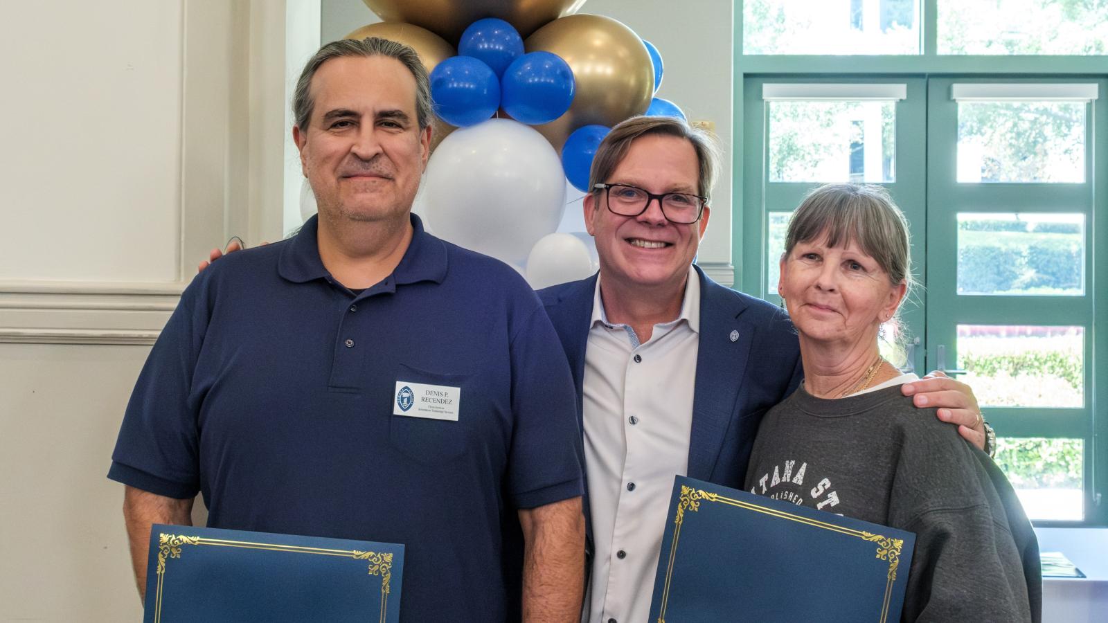 Two staff members in a photo with Bob Gaines