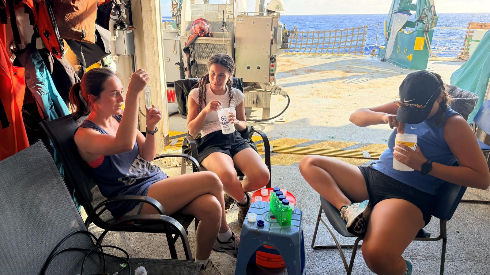 Students sit working on deck of boat