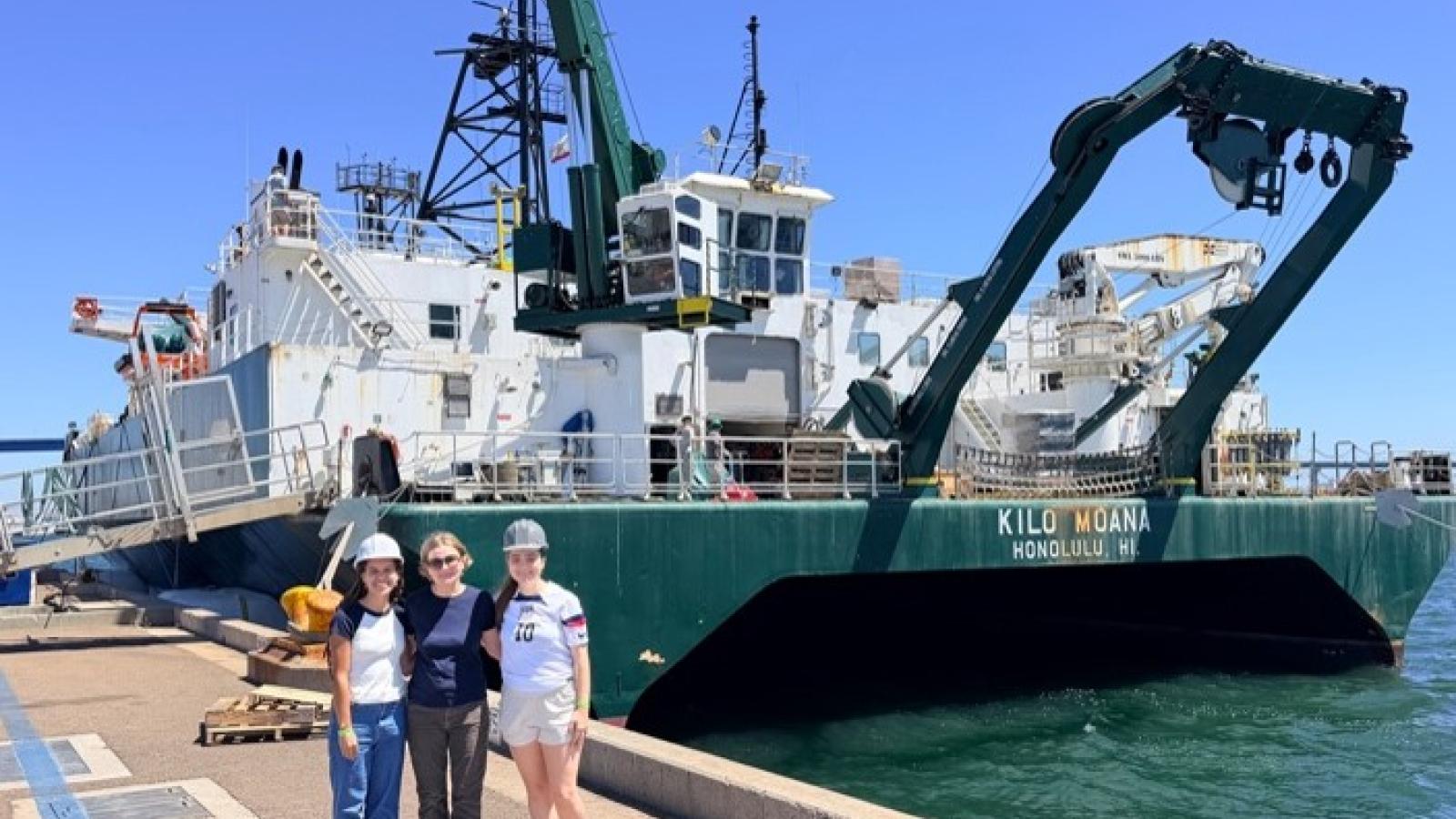 Masha prokopenko, Elle Hawthorne and Charlotte Renner pose next to the research vessel