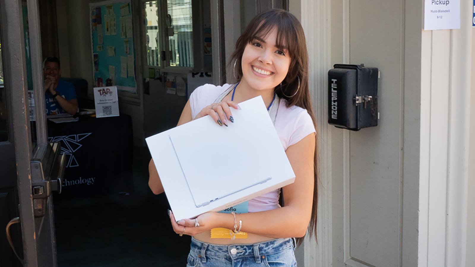 Student holding laptop in front of Mudd-Blaisdell