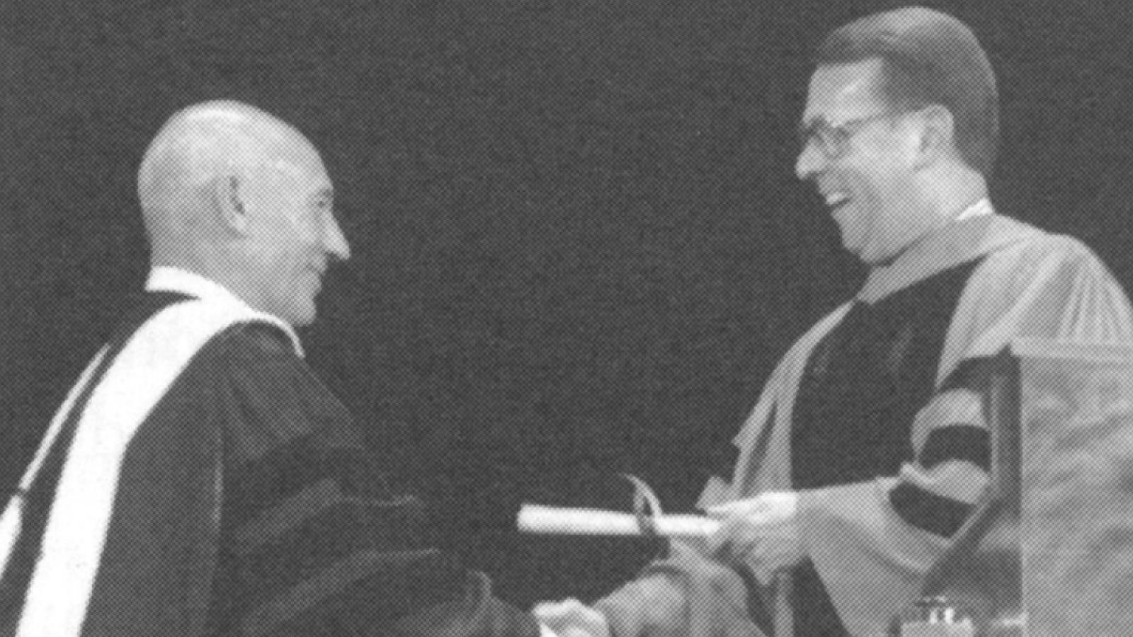 A man hands a degree to another man