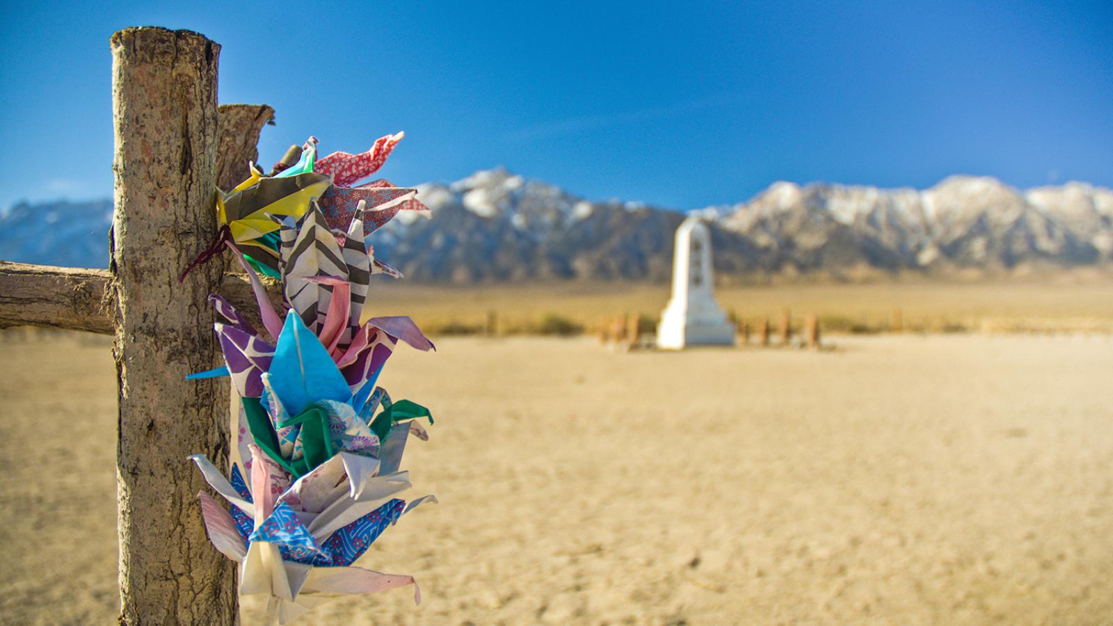 Manzanar monument with origami cranes in foreground and snow-capped mountains in background