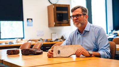 Robert Gaines holds fossil sample in geology lab