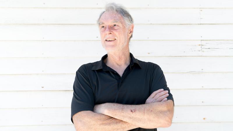 Professor Gary Smith standing in front of a white wall with arms folded across chest.