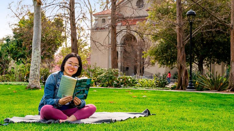 Student reads a book on Marston Quad