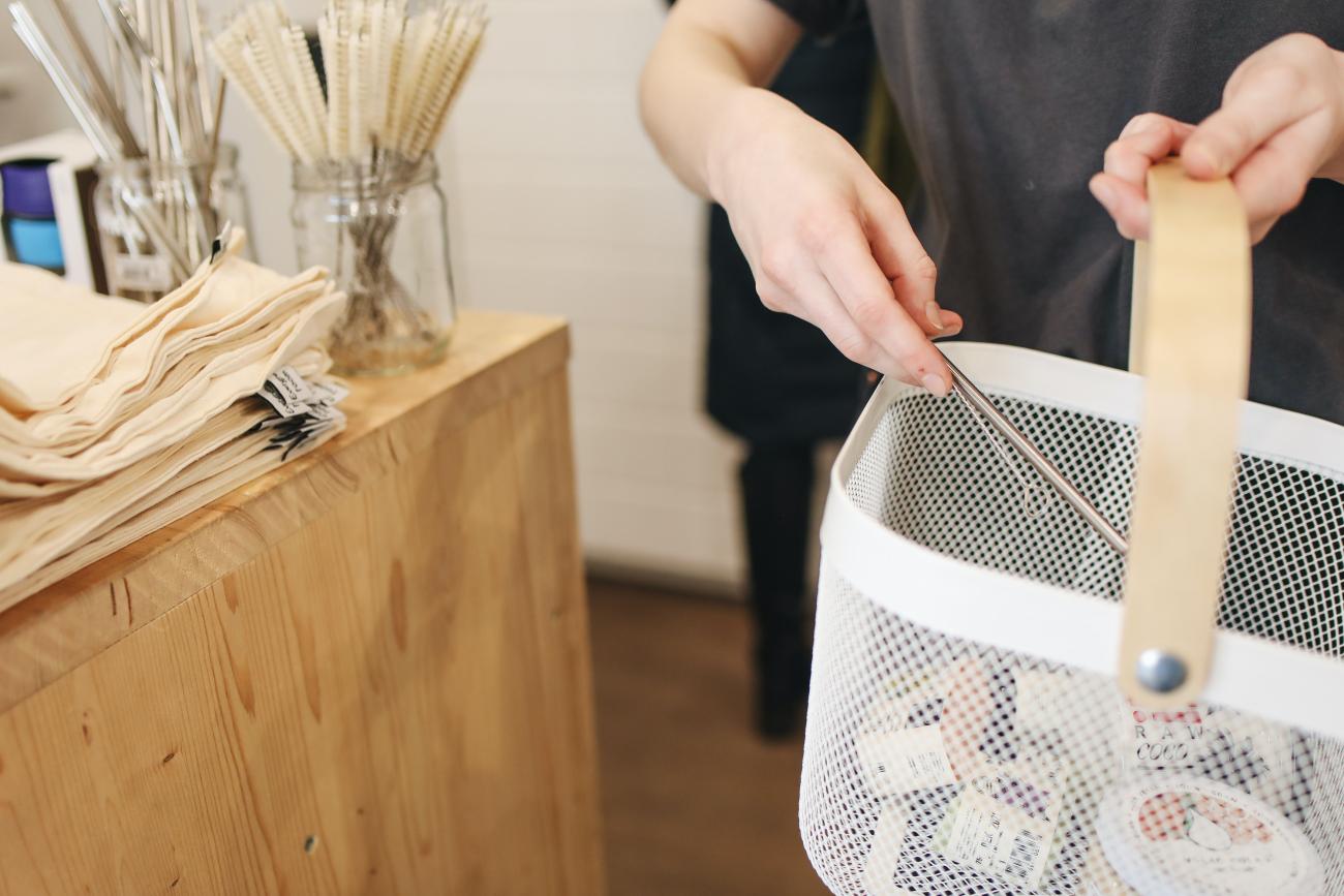 Person gathering items into a shopping basket, like a metal straw