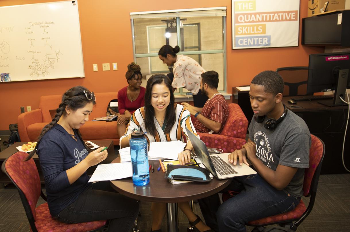 students around table in Quantitative Skills Center, working on laptops