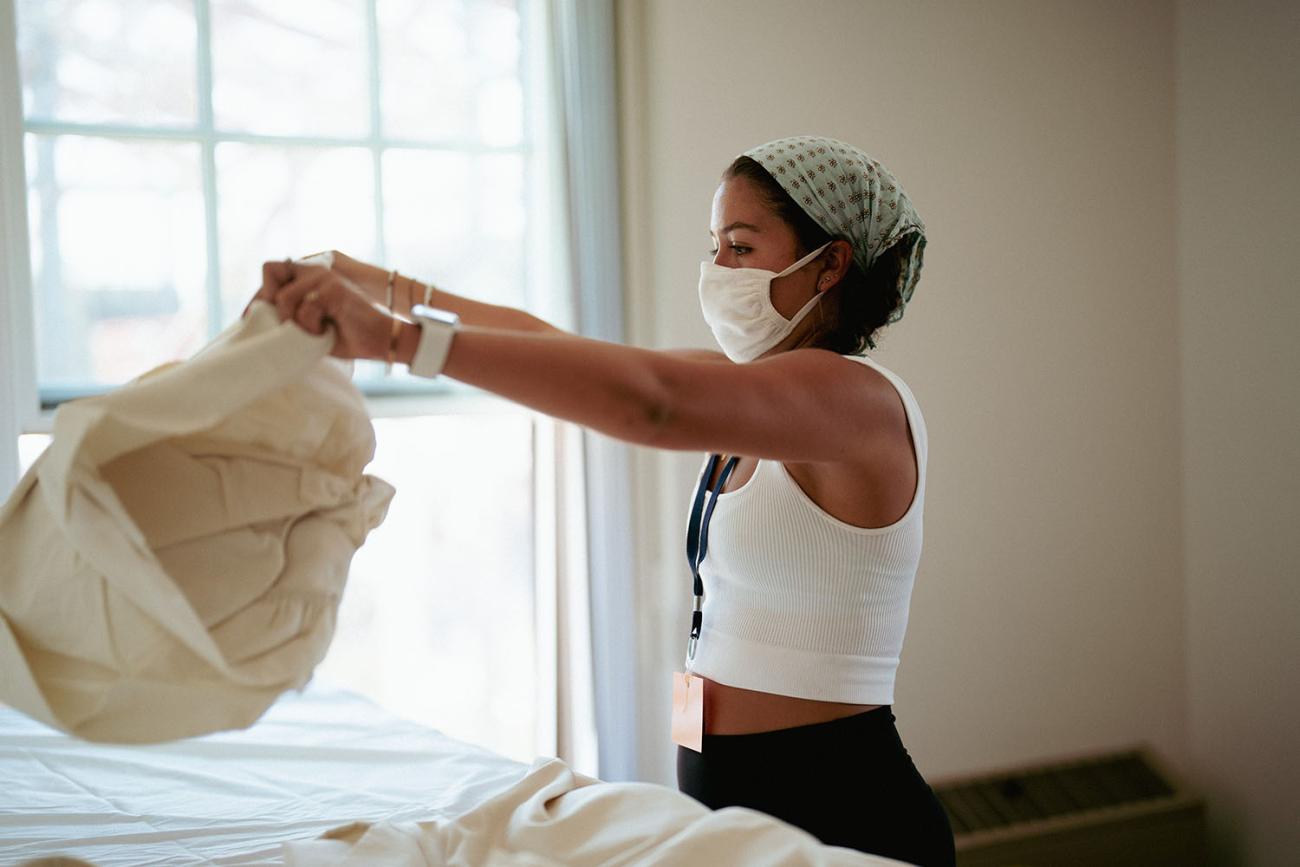 student makes bed in new room 