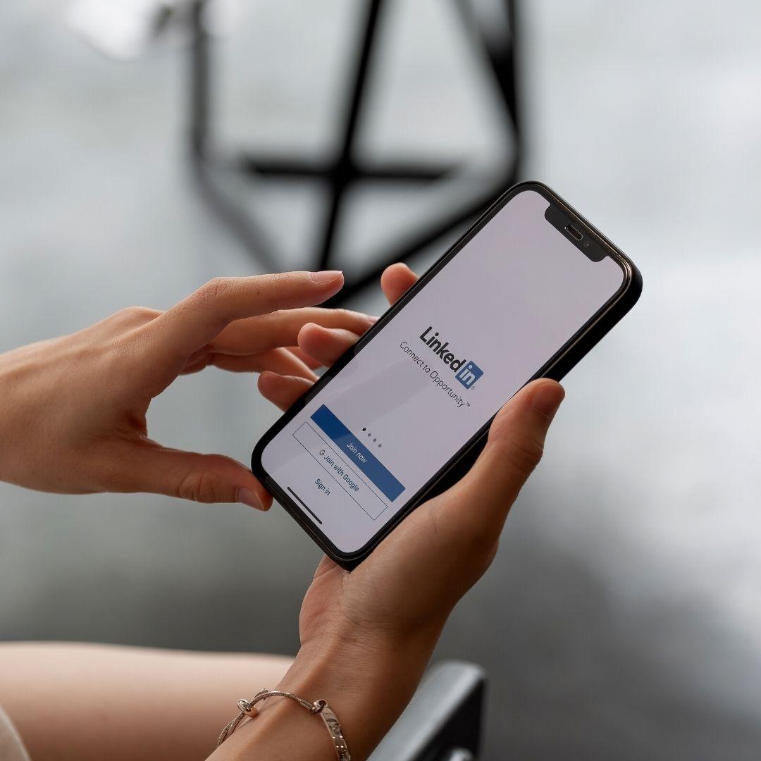 Hands holding a phone with LinkedIn on the screen