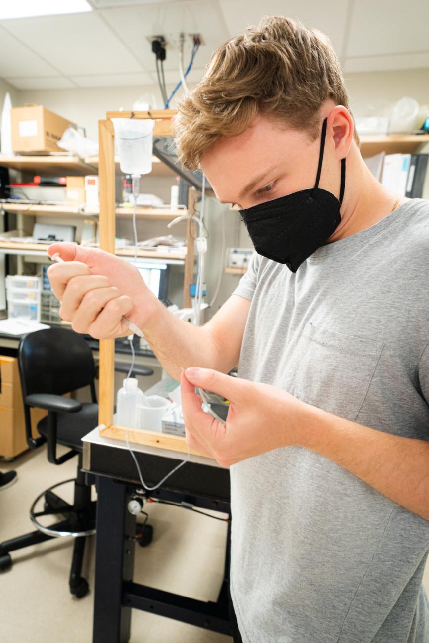 Student in Professor Jonathan King's neuroscience lab holds a research instrument.