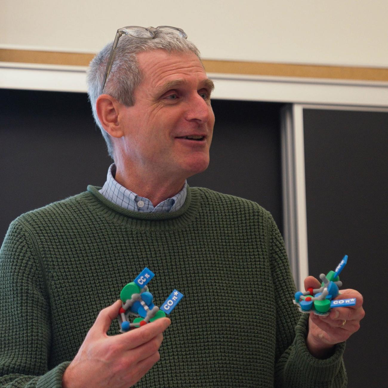 Professor Daniel J. O'Leary holds an orbital model in each hand in organic chemistry class