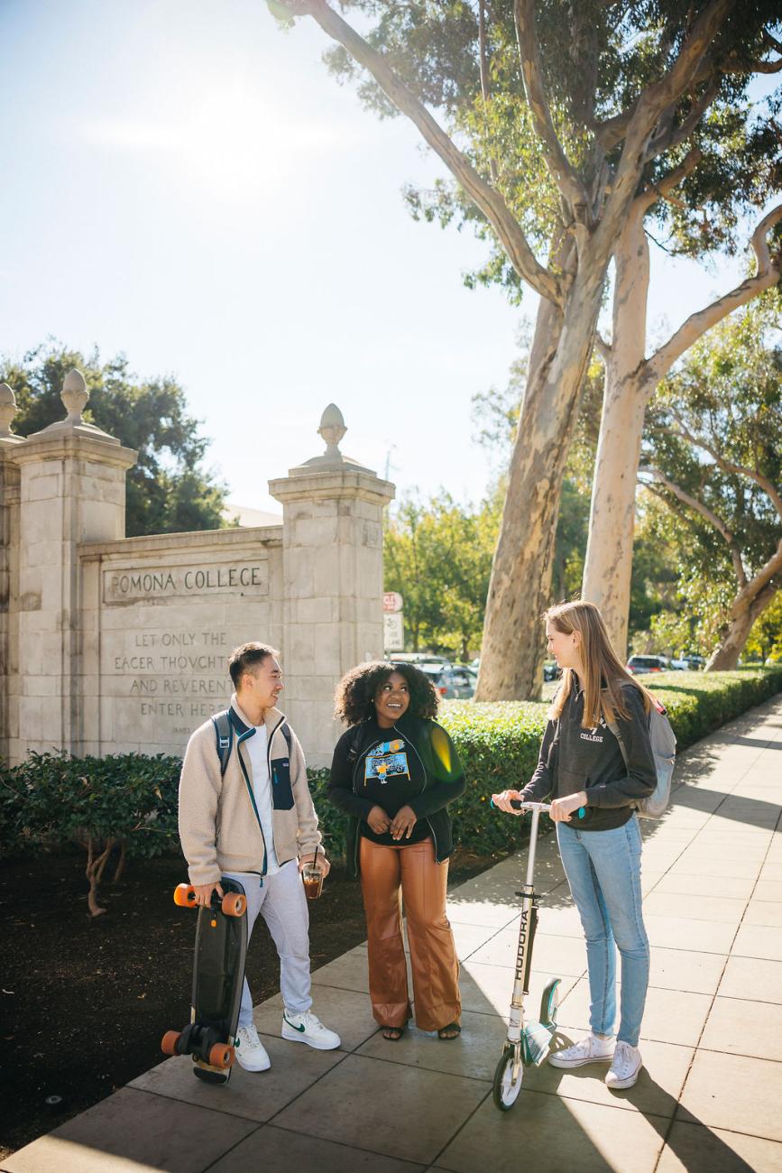 three students standing in front of Pomona College gates