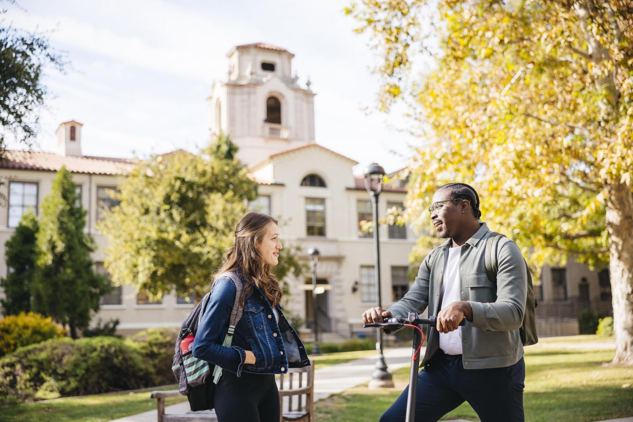 two students stand outside of a residence hall talking