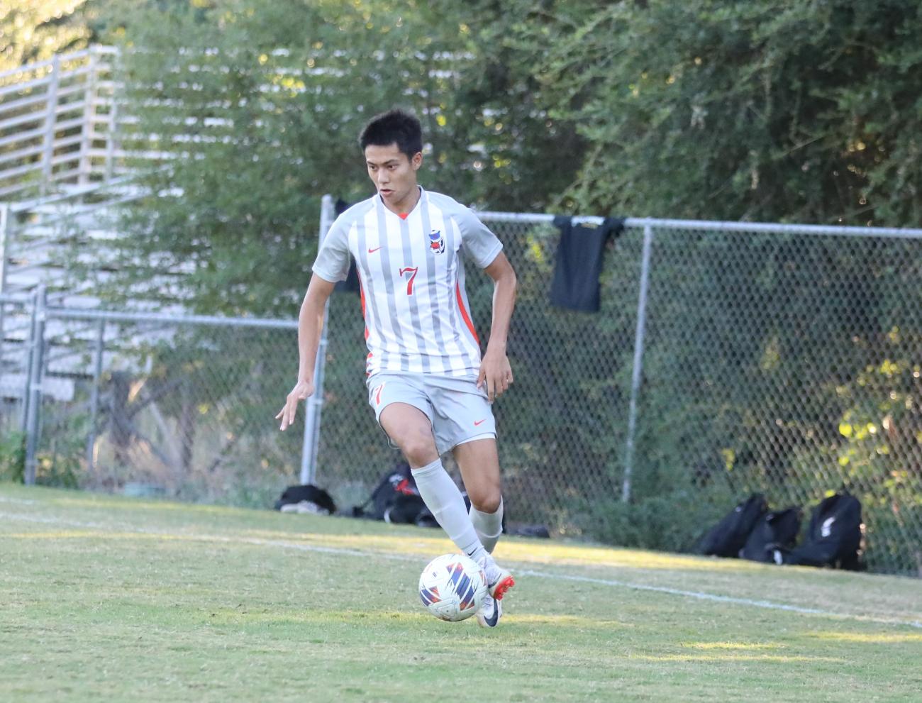 Kyle Lau dribbles a soccer ball during a game