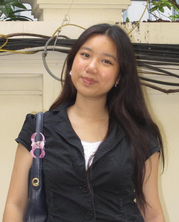 An Asian American female student with long black hair stands in front of one of the gates to Pomona College