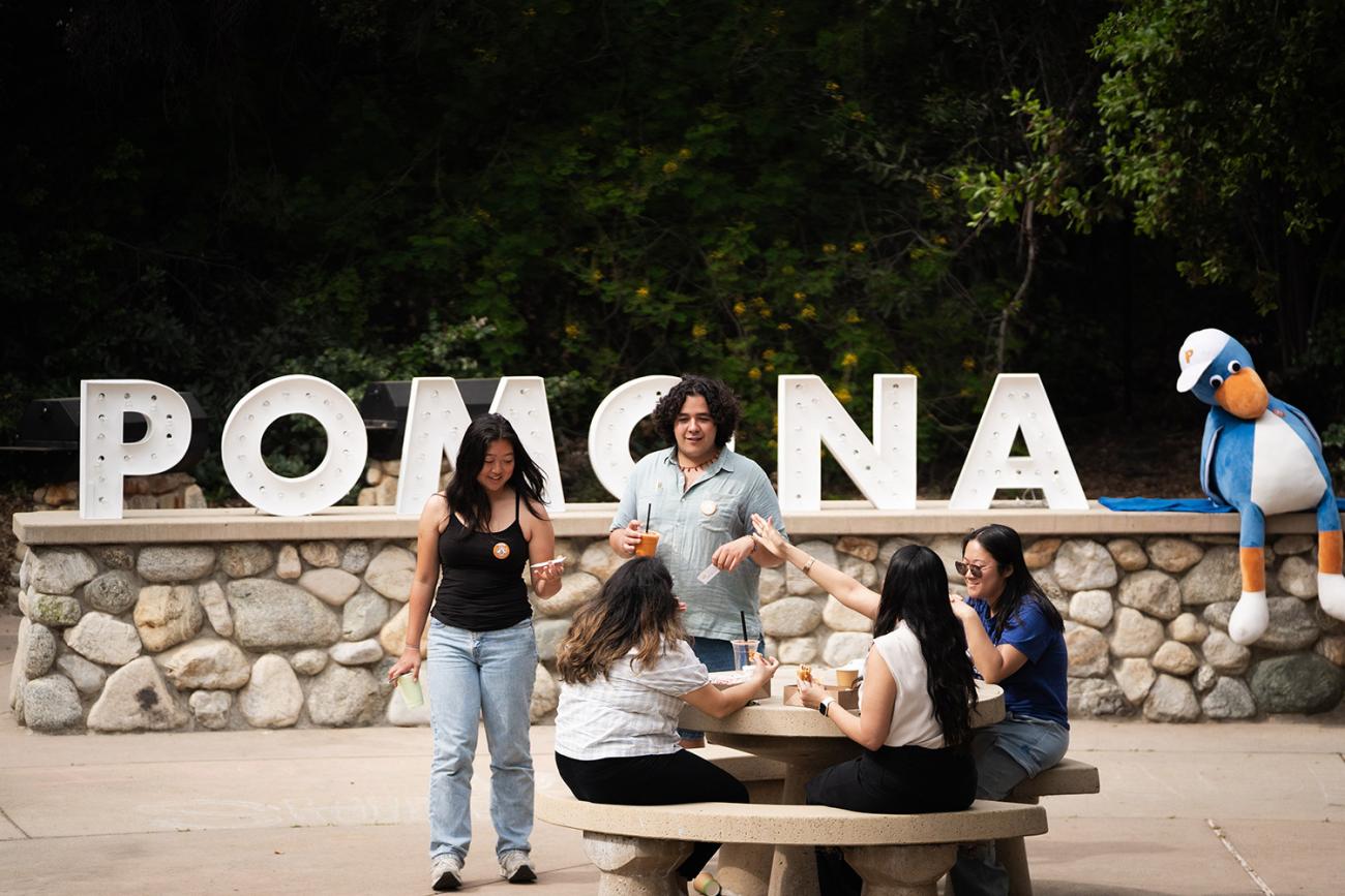 Students around a table with a Pomona sign behind them