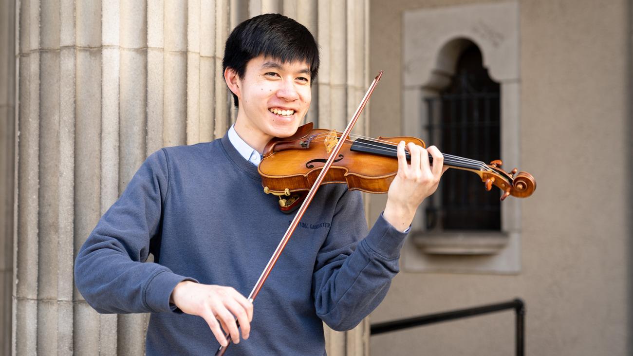 Student practices violin on steps of Bridges Hall of Music