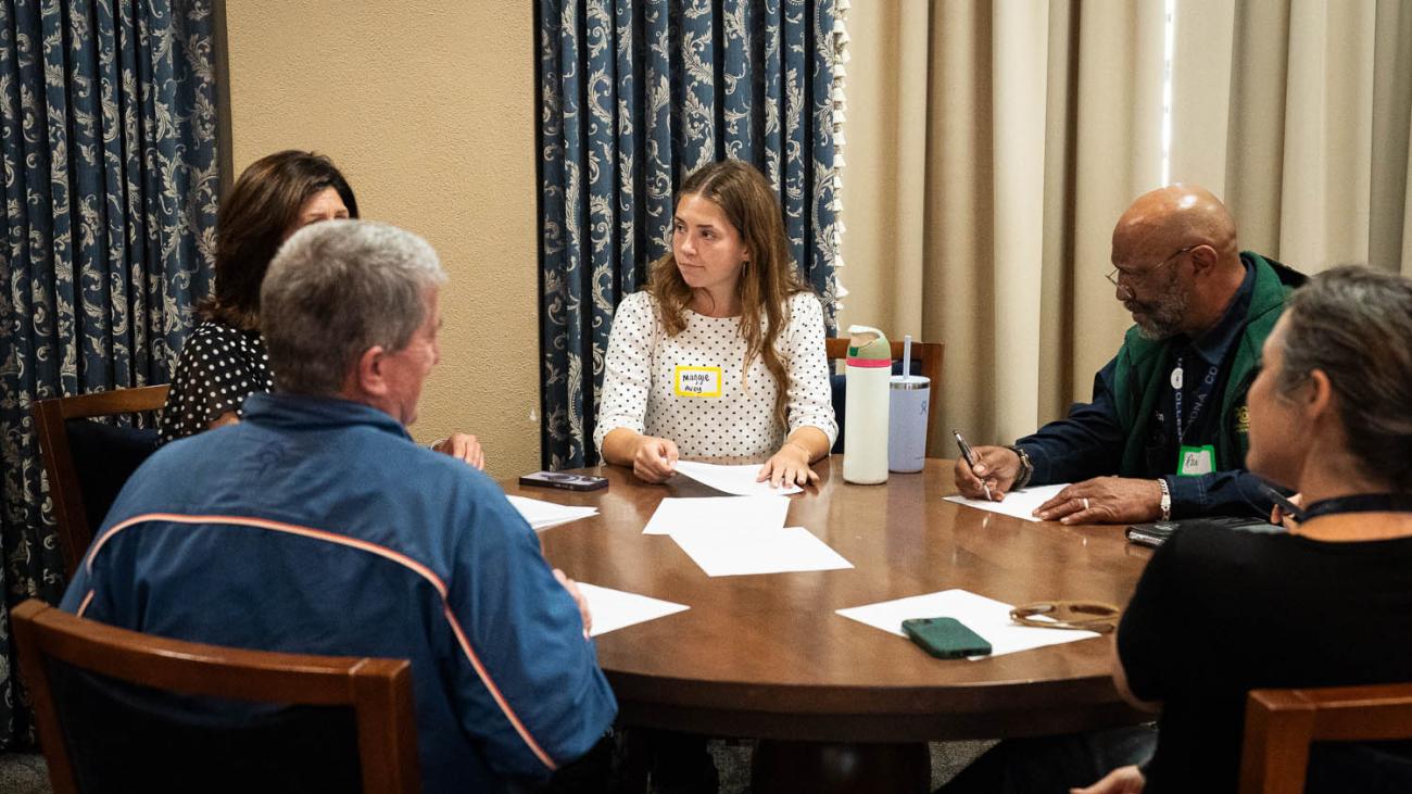 Faculty, staff, and students discuss the talk around a table.