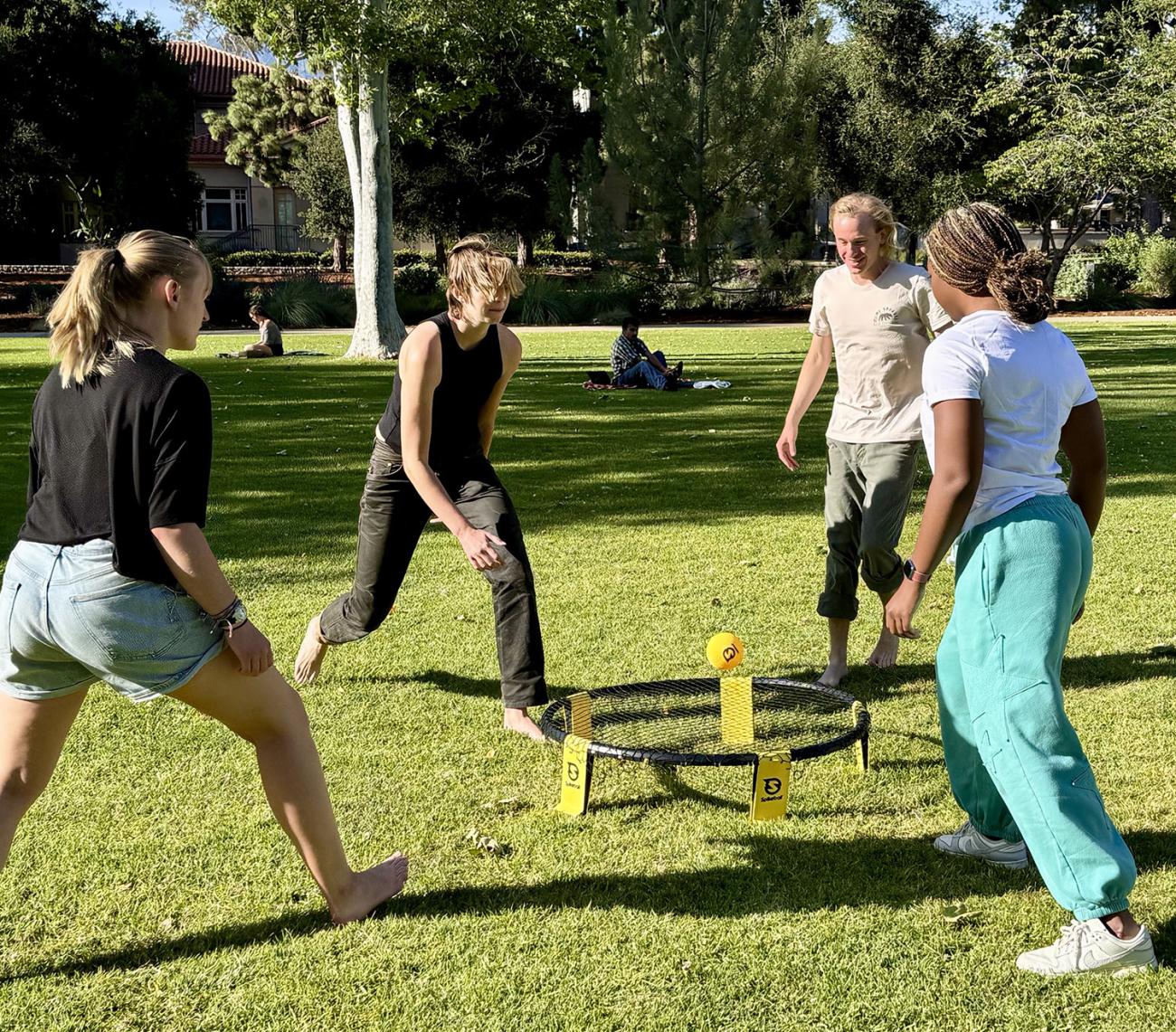 Four students play spike ball on Marston Quad.