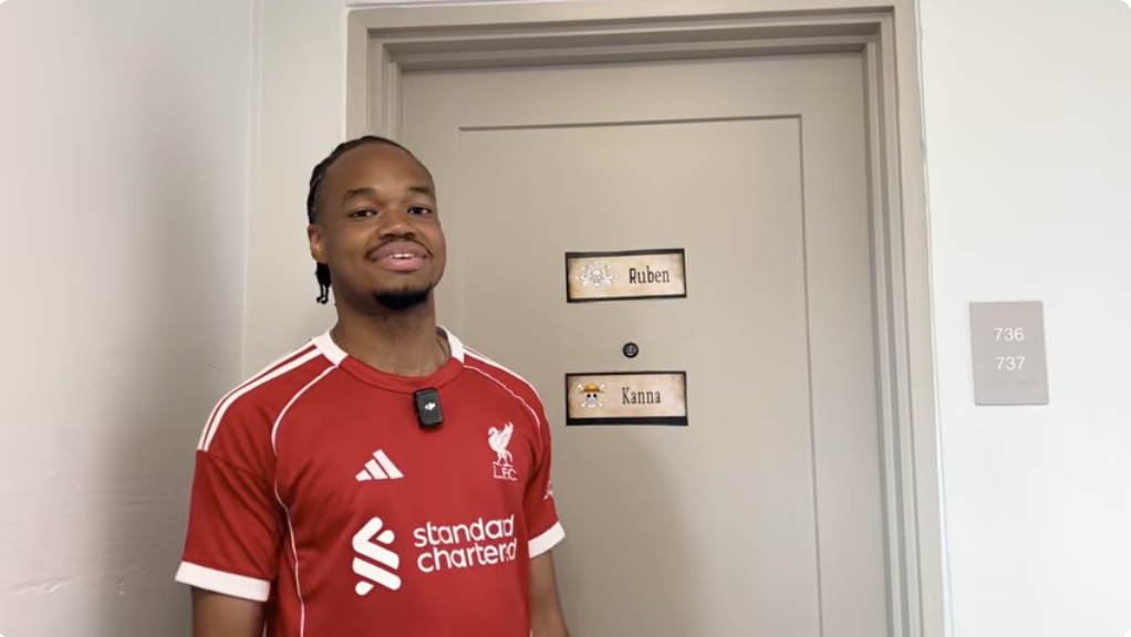 Student stands in front of dorm door smiling
