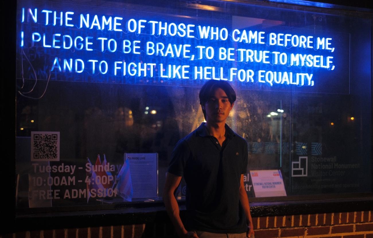 Man in front of neon signage at the Stonewall Historic Site in New York City