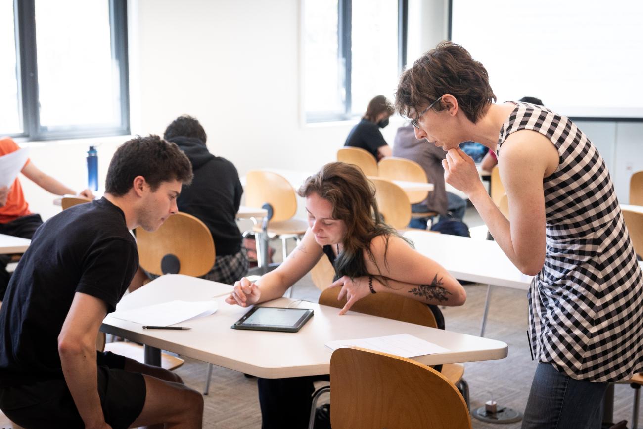 Two students and a professor look at an iPad