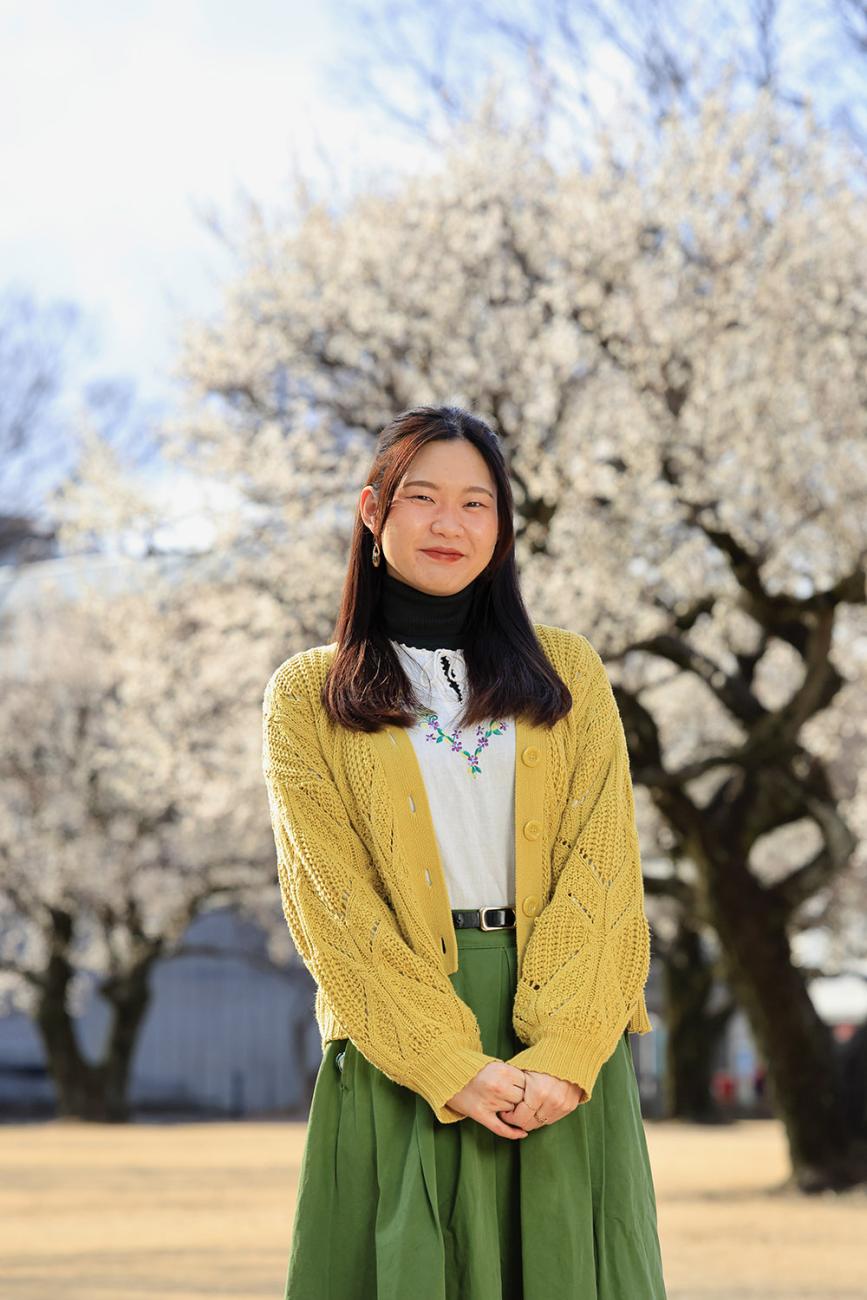 Japanese Language Resident Wako Sato standing in front of cherry blossoms