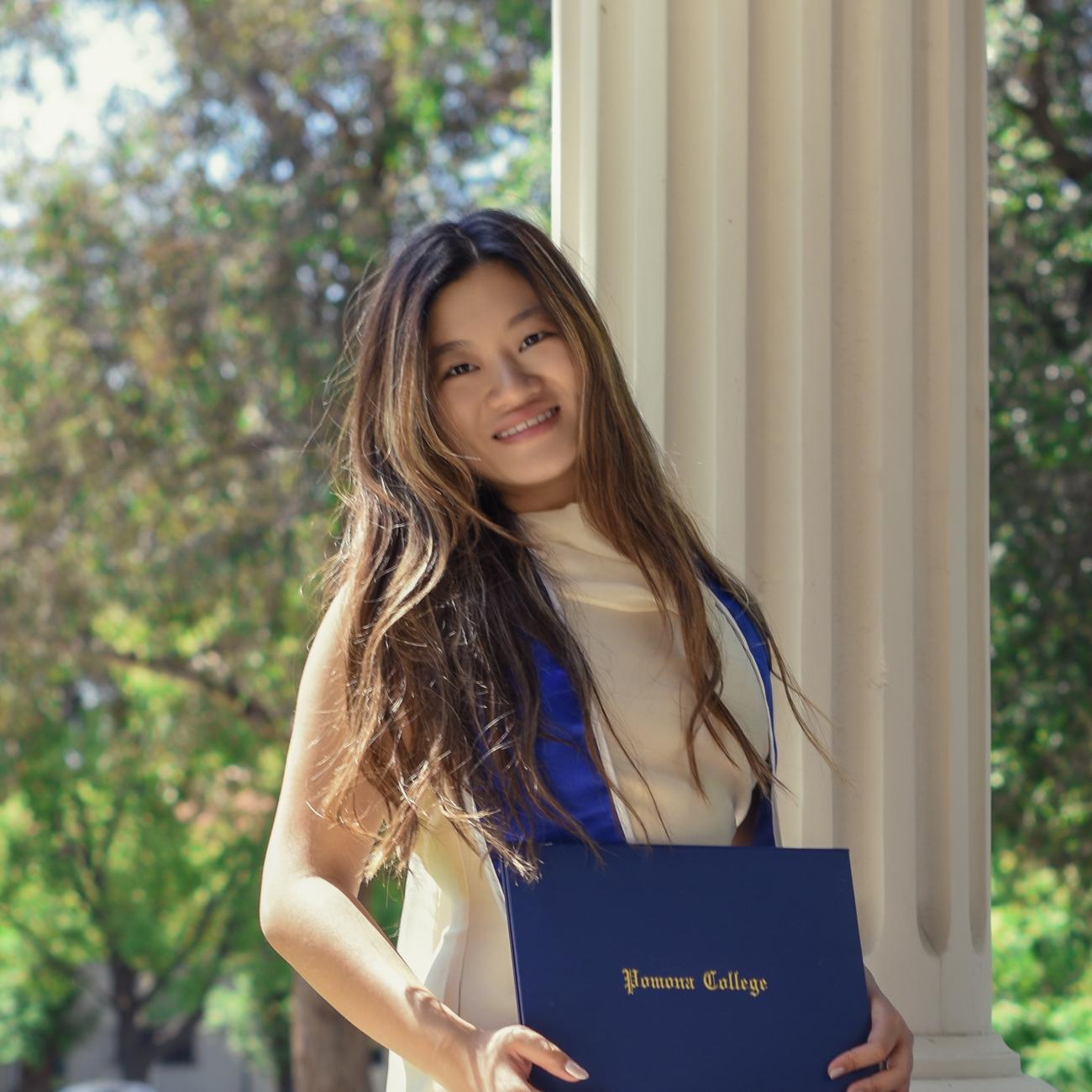 Shurui Lai holds her diploma on the Pomona College campus.