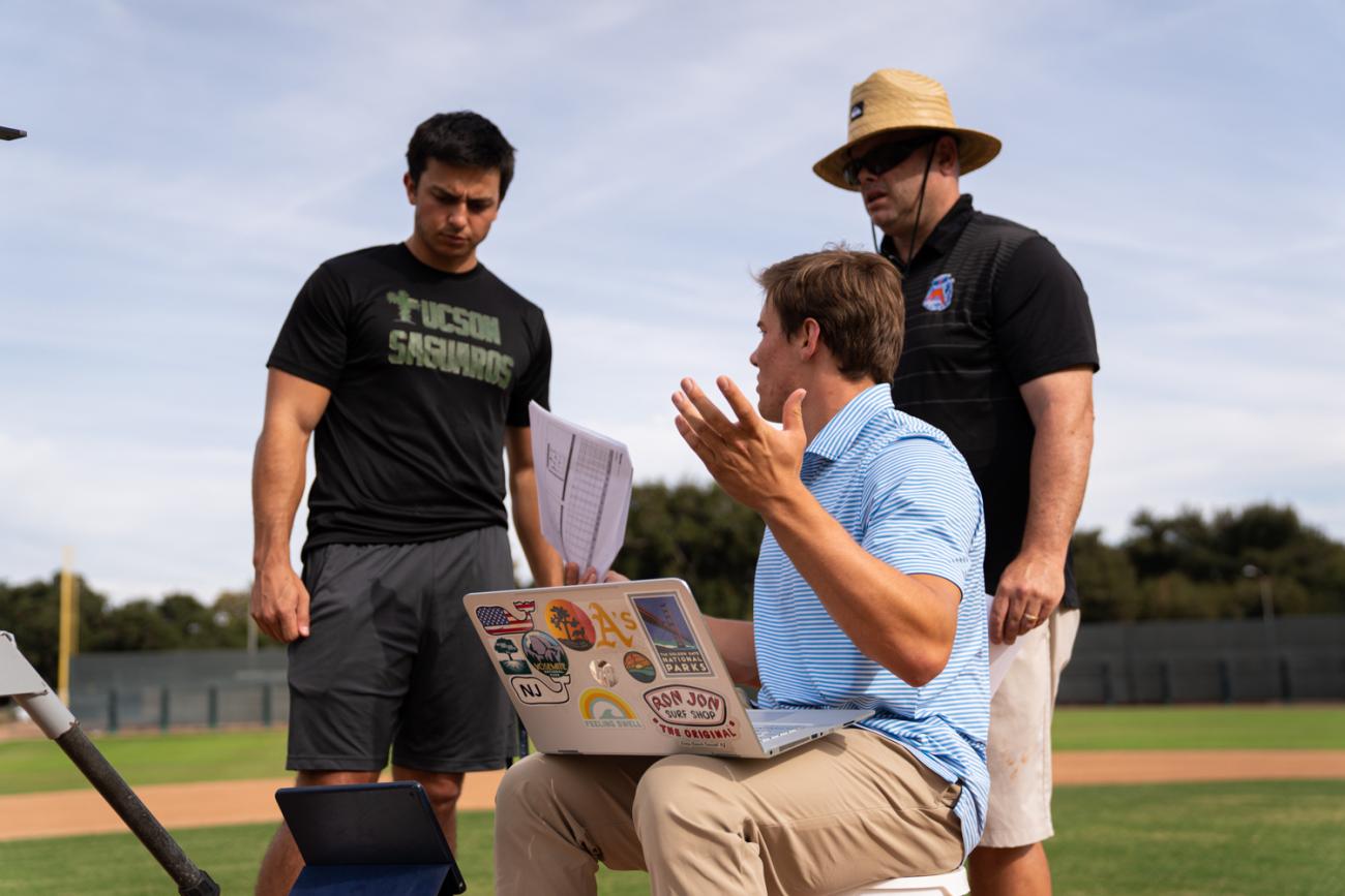 Students Jake Lialios and Jack Hanley discussing data with Coach Frank Pericolosi