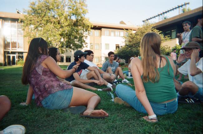 Students sit in a circle on the grass