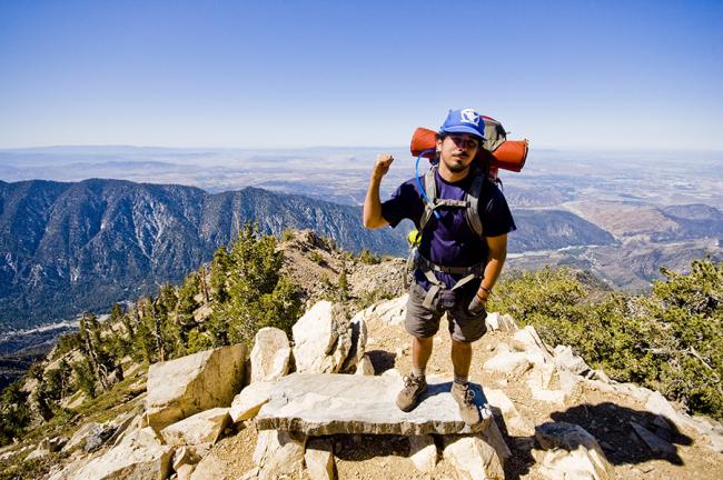 A student stands at the summit of a mountain