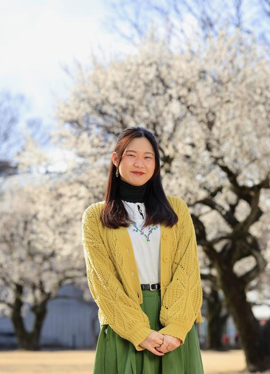 Japanese Language Resident Wako Sato standing in front of cherry blossoms