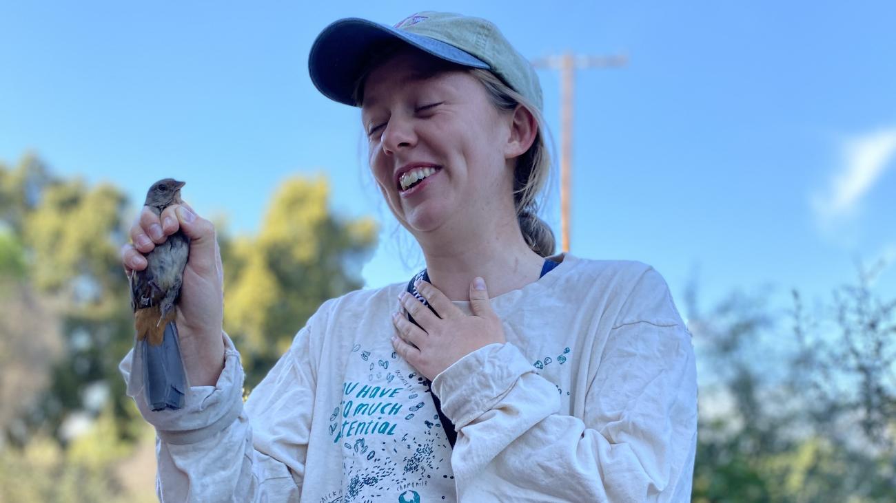 Photo of Alexandra Lintner with big smile, holding a bird for an animal ecology class observation