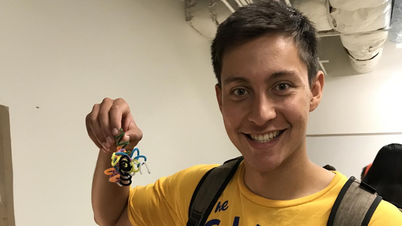 Photo of Jonathan Contreras with big smile, holding up a project for a biology course