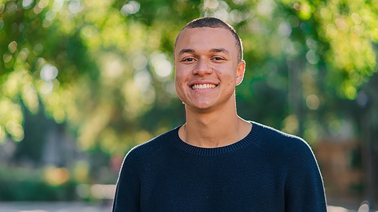 Young man wearing a black sweater and smiling into the camera