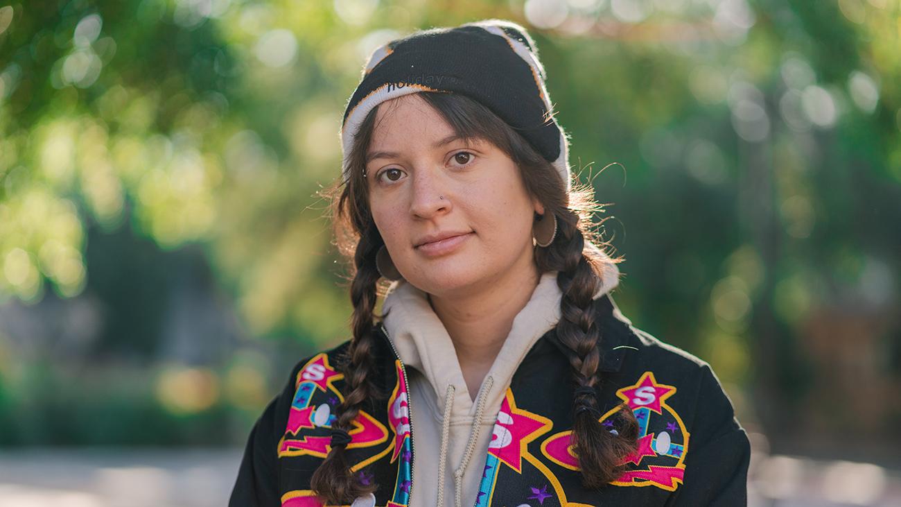 Young woman wearing colorful jacket and beanie and smiling into camera