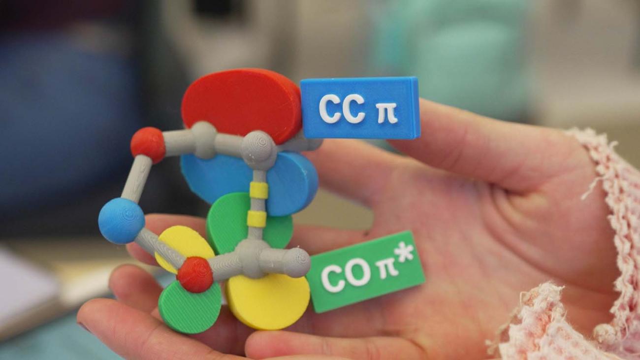 Hands holding colorful model of molecular orbital