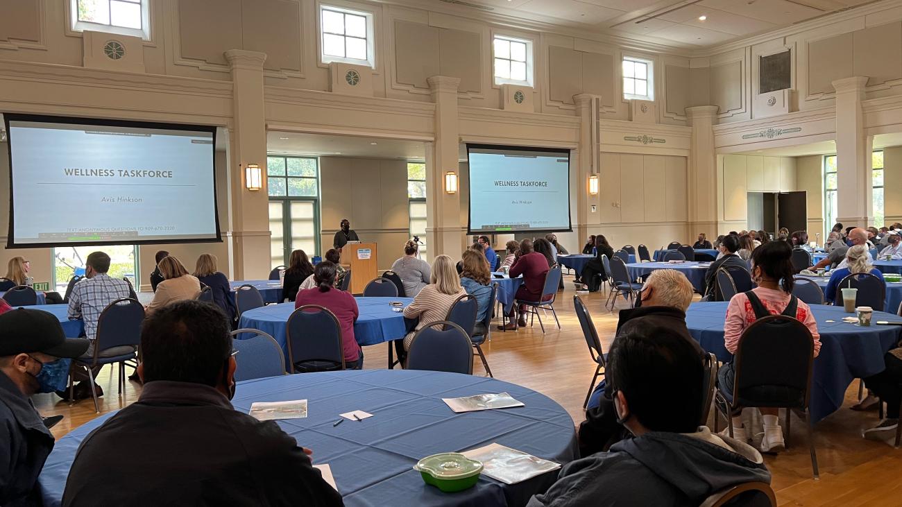 People sitting at round tables watching a presentation.