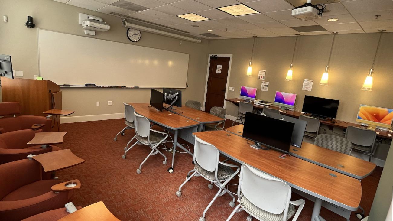 Classroom and lab section of the FLRC showing 27inch monitors, tables chairs, and imacs along the back wall.