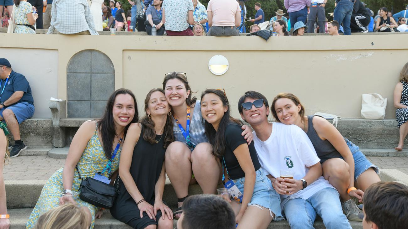 A group of alumni sit together and smile