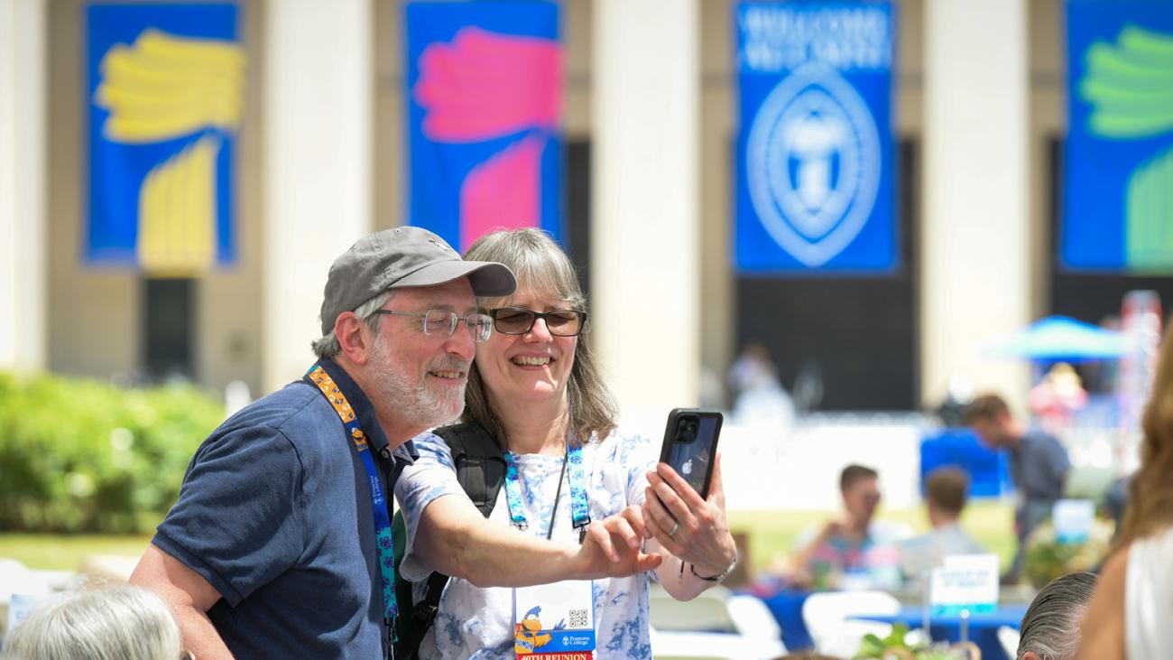 Two alumni take a picture in front of Pomona College banners