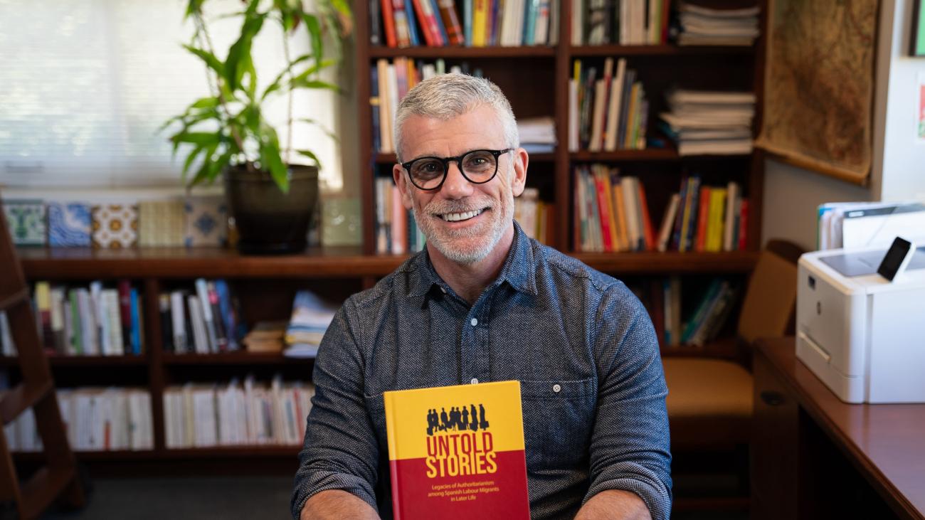 Prof. David Divita holds his new book in his office