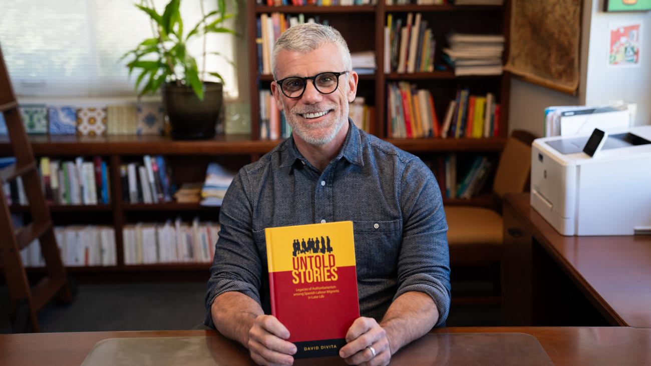 Prof. David Divita holds his new book in his office